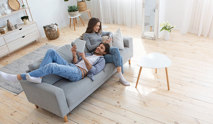Pärchen mit mobilen Endgeräten auf dem Sofa