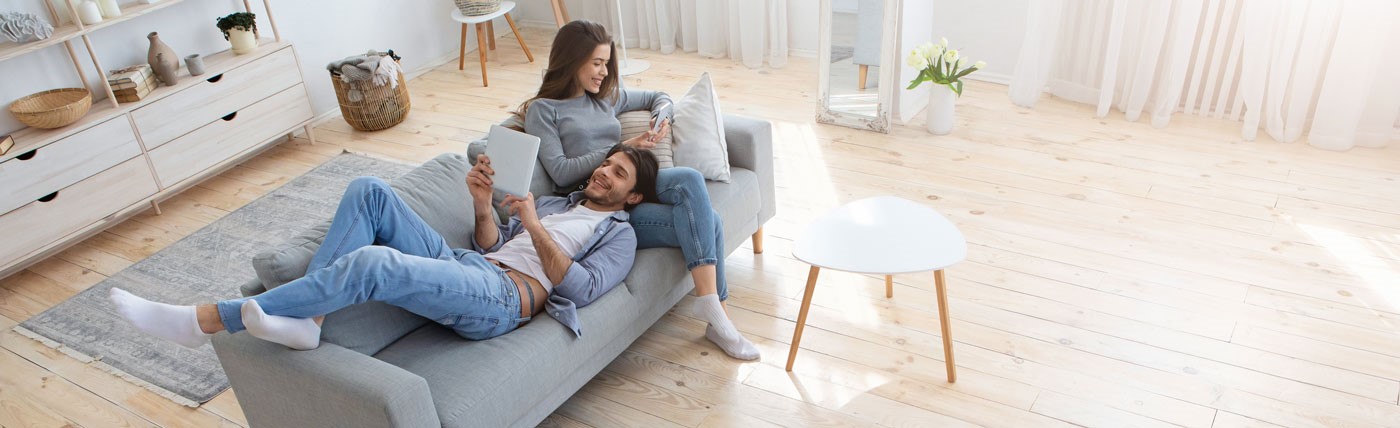 Pärchen mit mobilen Endgeräten auf dem Sofa